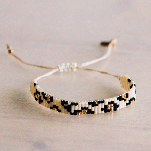 Deze gevlochten armband met kralen in luipaardprint gecombineerd met goud heeft een schuifknoop en is daardoor verstelbaar.